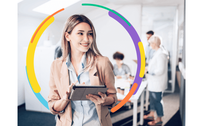 Foto de una mujer en la oficina sonriendo con su tableta en la mano, gestionando el alquiler de computadores para el desempeño de las labores de su equipo de trabajo.